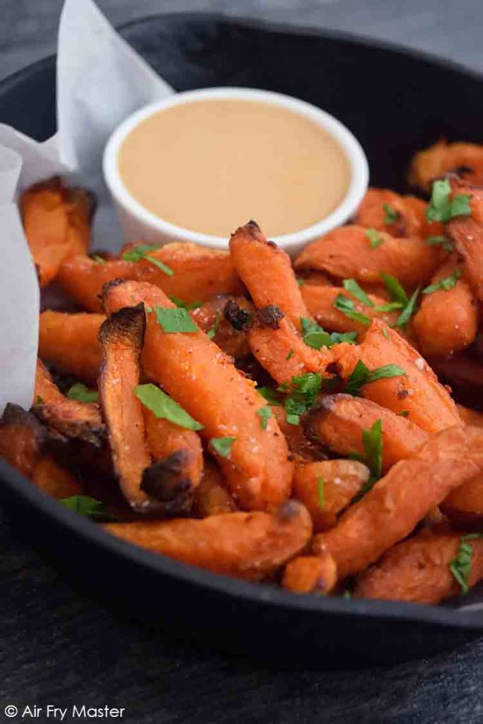A black skillet filled with Air Fryer Sweet Potato Fries and a side of fry dip.
