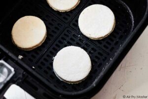 Air fryer biscuits sitting in the air fryer basket, ready to be baked.