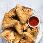 Cooked from frozen chicken wings on a round, white plate with red dipping sauce. One of many recipes in this guide to the best keto air fryer recipes.