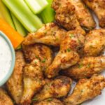 Extra Cruncy Air Fryer chicken Wings on a serving platter, next to celery stalks and ranch dip. One of many recipes in this guide to the best keto air fryer recipes.