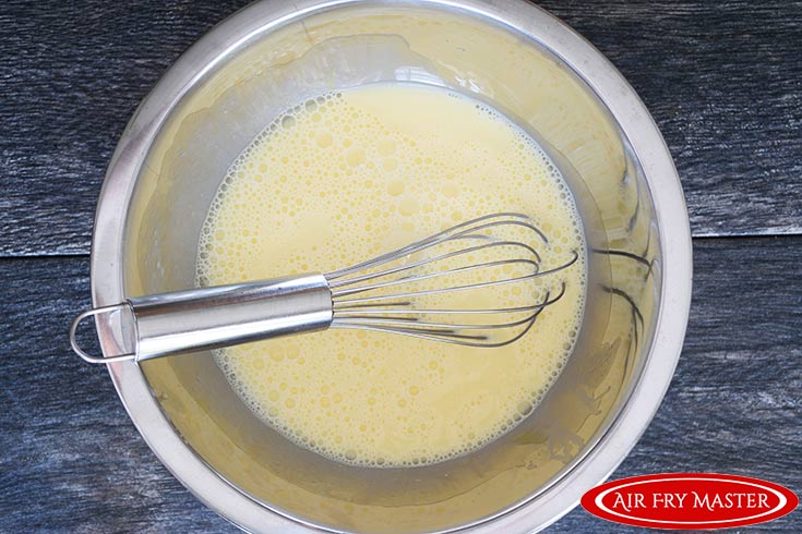 The eggs and milk whisked together in a mixing bowl.