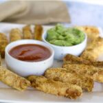 Air Fryer Halloumi Fries served with ketchup and guacamole on a white, square platter.