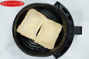 Two raw strudels in the air fryer basket, ready to cook.