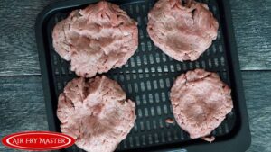 The formed turkey patties sitting on an air fryer tray, waiting to be air fried.