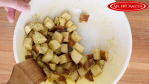 Stirring the potatoes to coat them in the oil and spices.