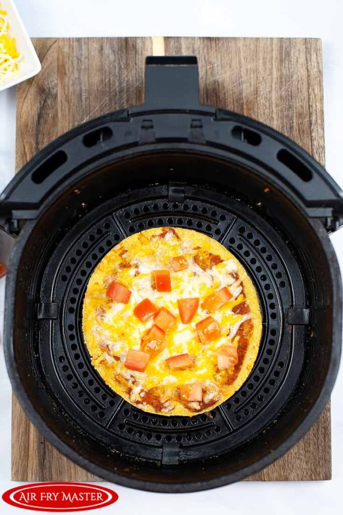 A cooked Air Fryer Copycat Taco Bell Mexican Pizza sitting in an air fryer basket, cooling.