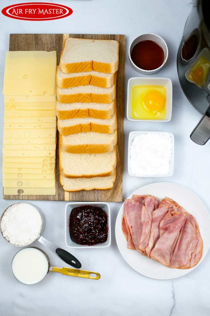 All ingredients for this Air Fryer Monte Cristo Sandwich Recipe gathered around a cutting board and air fryer.