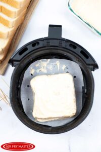 The Air Fryer Monte Cristo Sandwich covered in batter and sitting in a parchment lined air fryer basket.