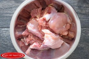 The raw chicken thighs sitting in a large mixing bowl.