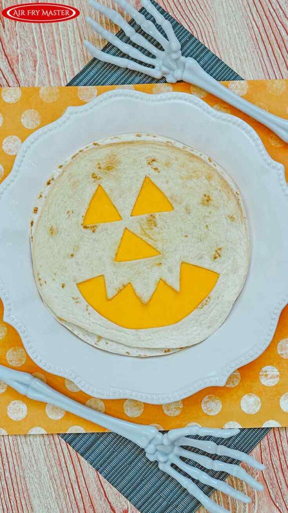 A single quesadilla on a white plate showing the final result of this Air Fryer Jack-O-Lantern Quesadillas Recipe
