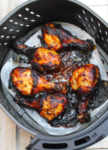 Air Fryer chicken legs, just air fried and still sitting in a parchment-lined air fryer basket.