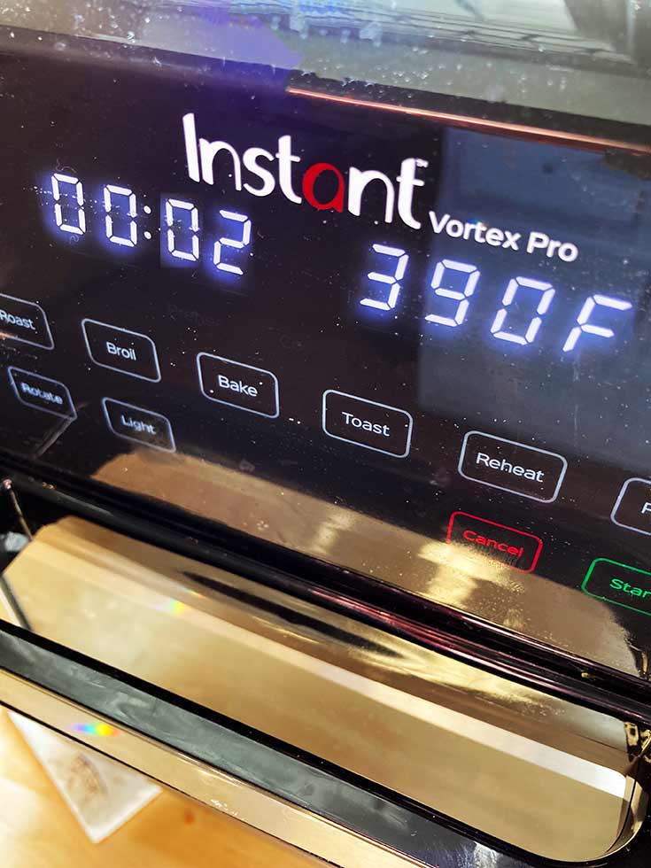 An air fryer display panel set to preheat at 390 degrees for 2 minutes.
