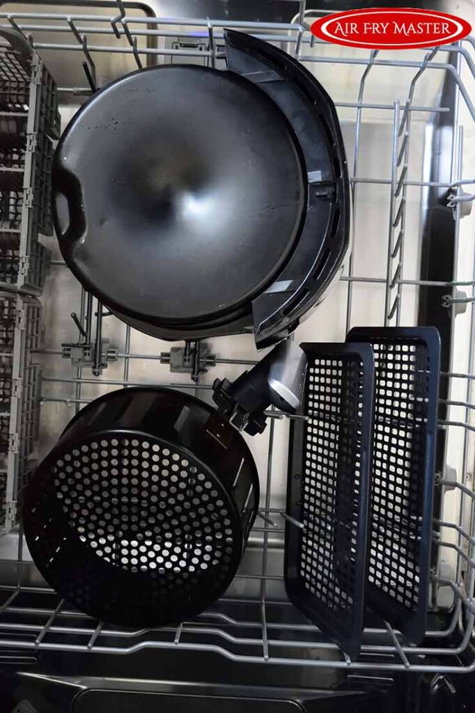 An air fryer basket and air fryer trays sit in a dishwasher rack.