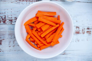 Cut, raw carrot sitting in a white bowl.