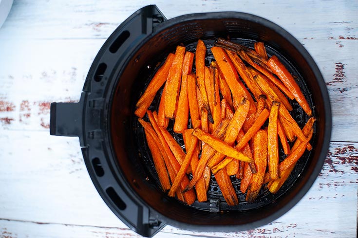 Just cooked carrot fries sitting in an air fryer basket.