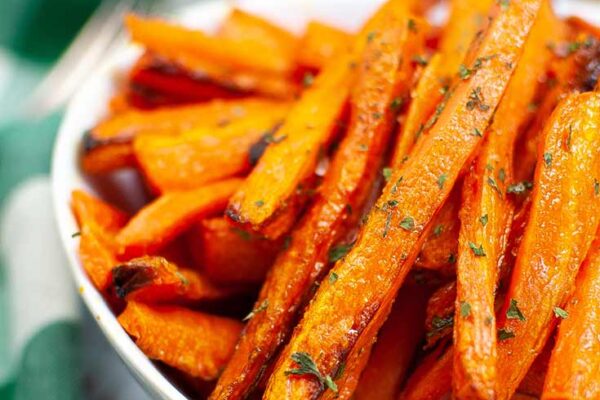 Close up of a white bowl filled with Air Fryer Carrot Fries.