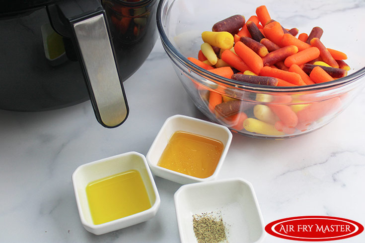 All the ingredients for this Air Fryer Glazed Carrots Recipe in separate bowls on a white, marble surface.