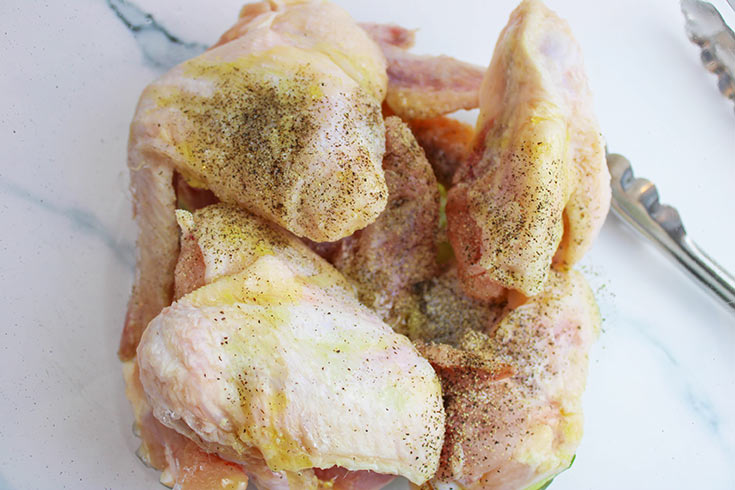 Raw chicken wings coated in oil and pepper.