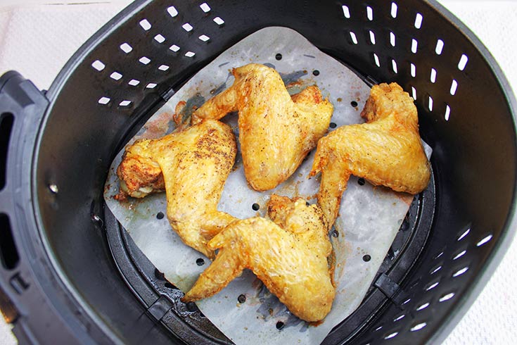 Just cooked chicken wings still sitting in a parchment lined air fryer basket.