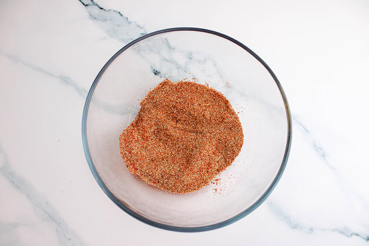 Dry spices mixed together in a clear glass mixing bowl.