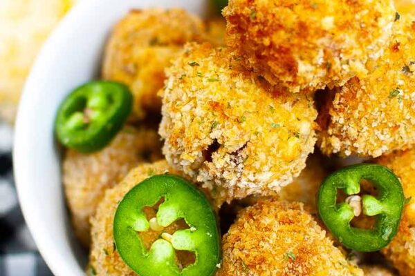 A close up view of a white bowl filled with Air Fryer Jalapeño Popper Bites and garnished with slices of jalapeno peppers.