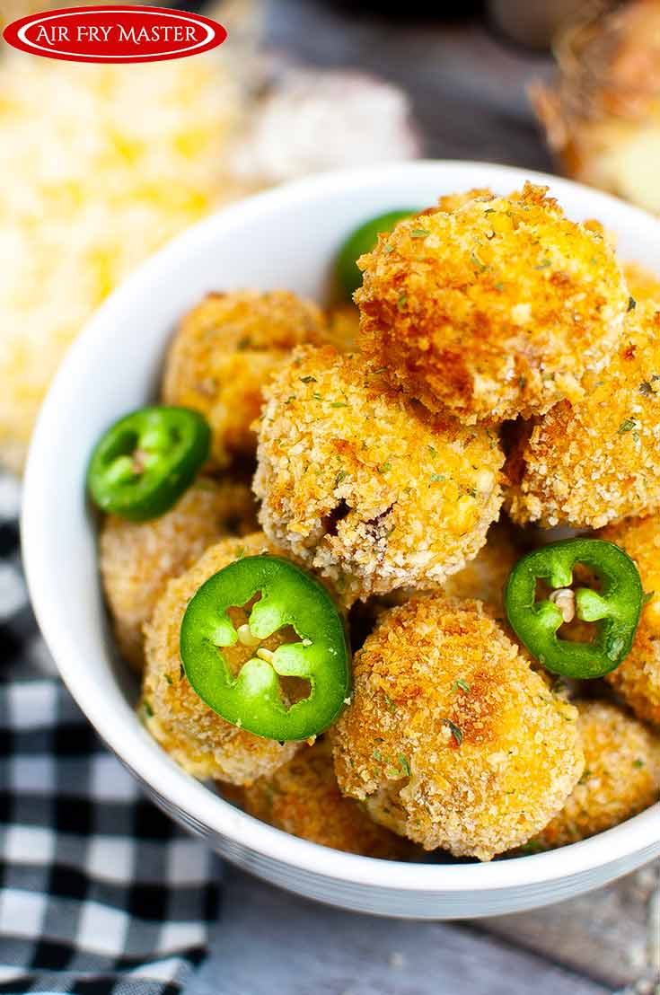 A close up view of a white bowl filled with Air Fryer Jalapeño Popper Bites and garnished with slices of jalapeno peppers.