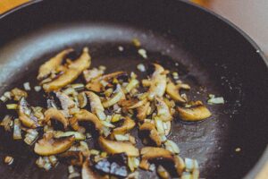 Mushrooms and onions sautéing in a black skillet.
